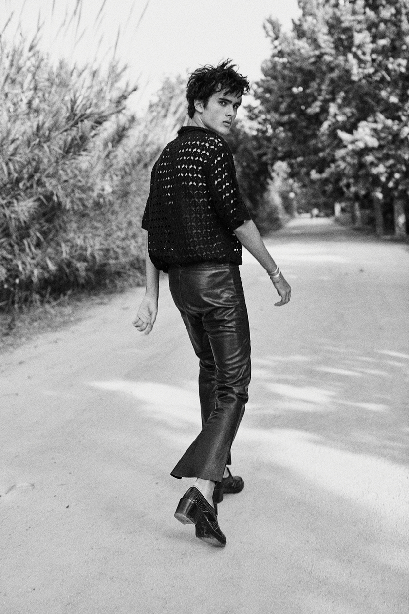 Blach and white picture with model Juan Reyes walking backwards in Saint Laurent pants 
