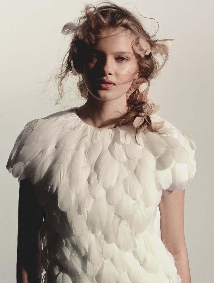 Photo taken by Daniel Scheel with model Vesta Matulytė wearing a dress made of white feathers and some pink feathers on her hair. 