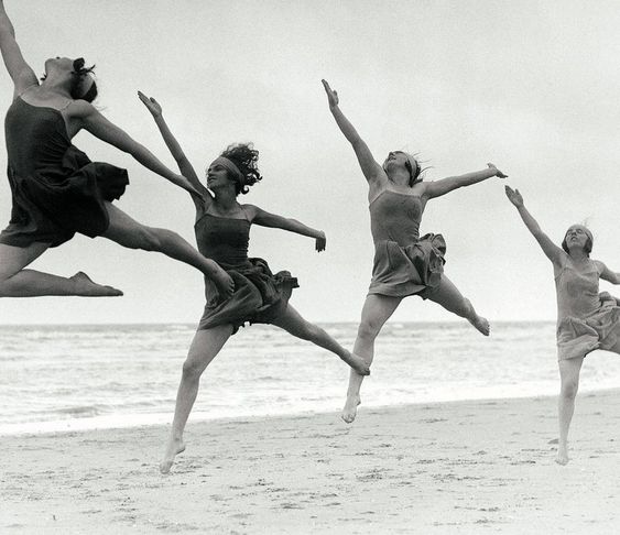 Four women dancing and jumping on the beach celebrating life as the 8AM production agency celebrates the beginning of the year. 