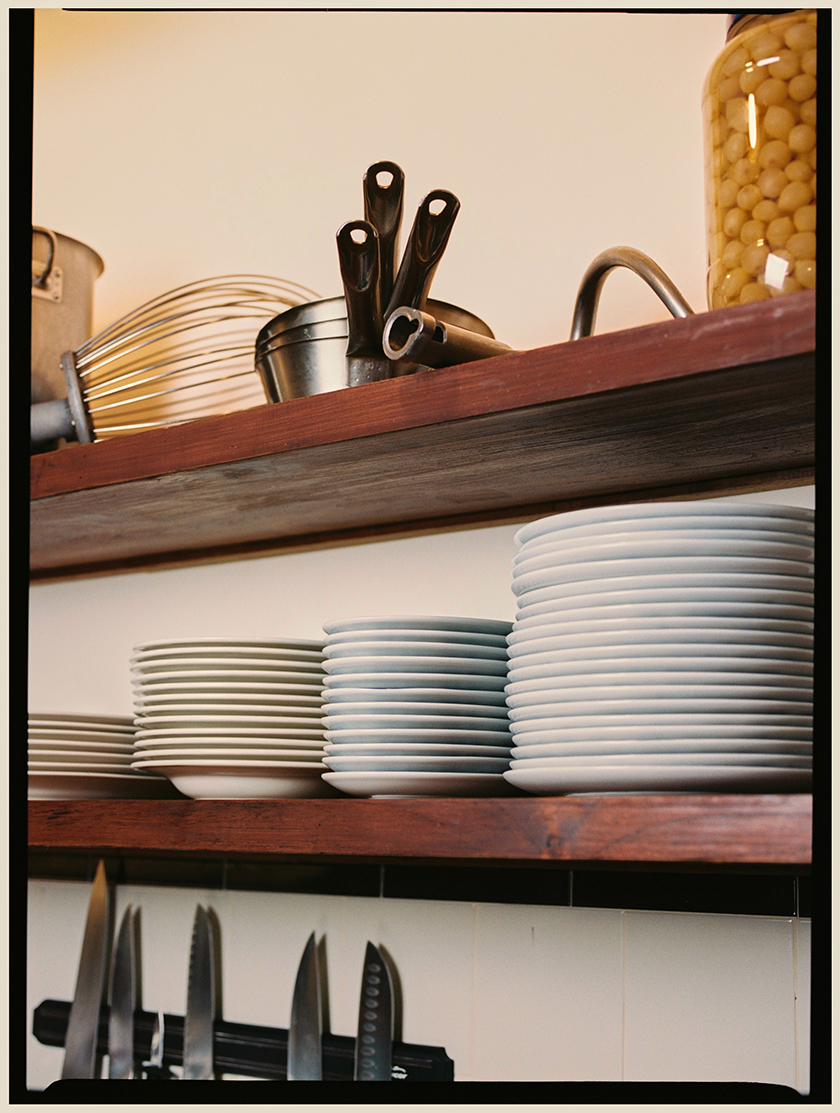 Shelves with plates and kitchen utensils at La Esquina bar.