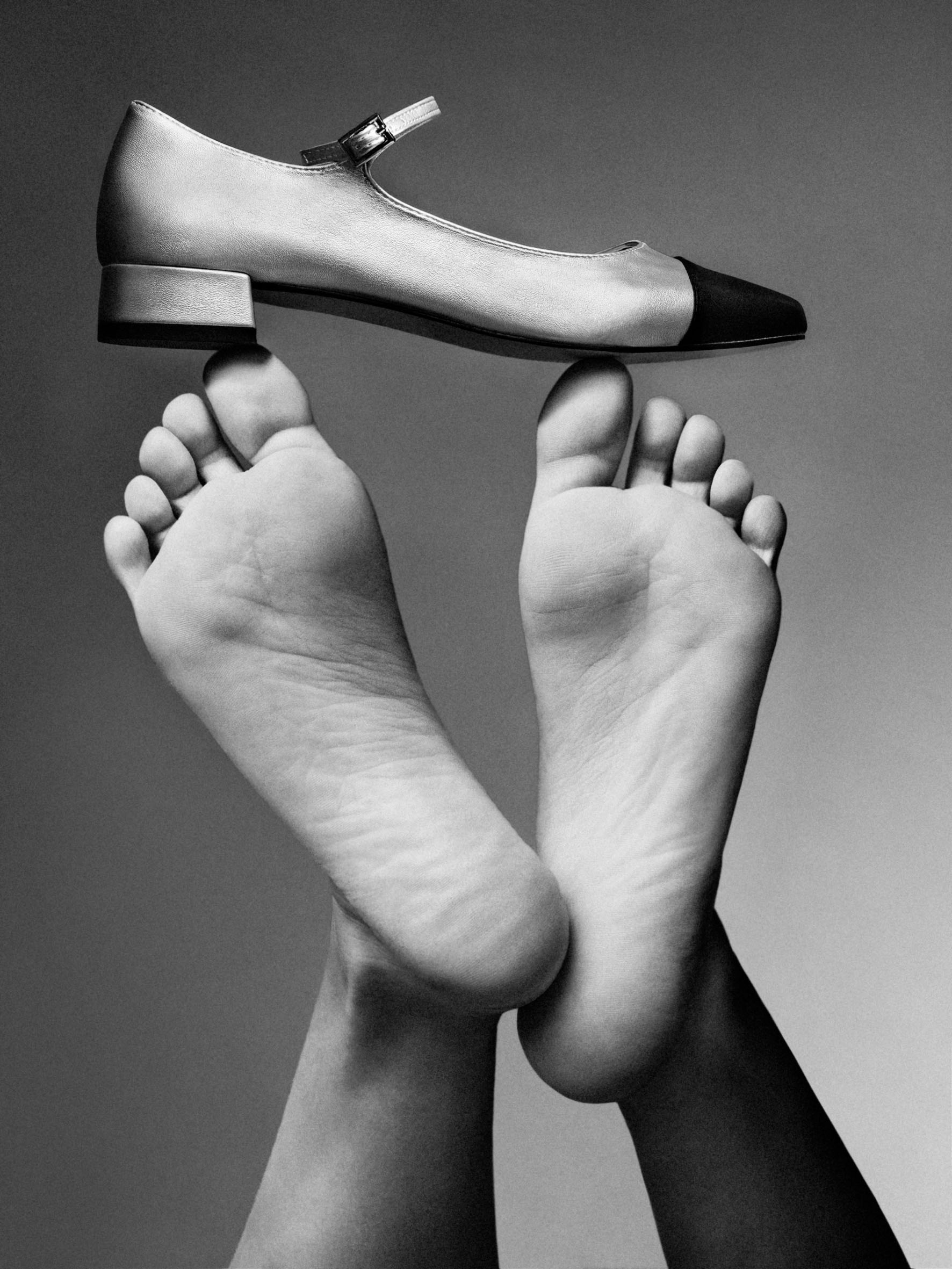 image of two feet holding a sandal in black and white