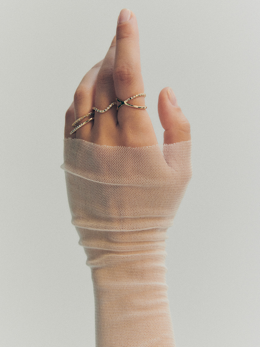 Shot of a hand with a tulle shirt with several shining rings from the new collection of the Prunés campaign. 