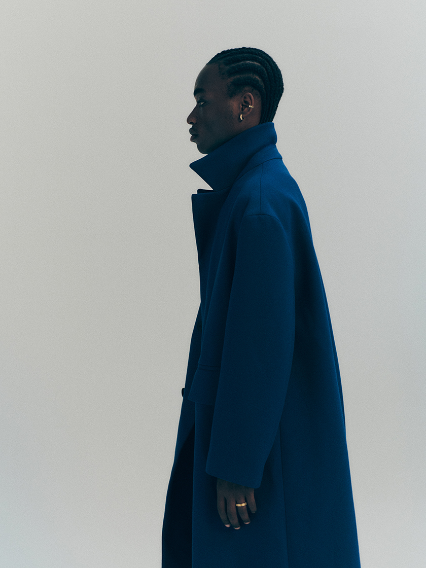 Image of the boy model with a long navy blue coat and jewellery from the new Prunés Jewellery collection.