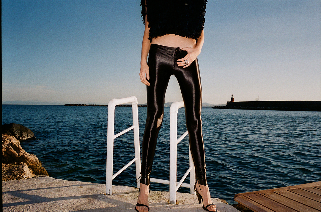 Photo of a woman's legs in front of the sea wearing leather leggings 