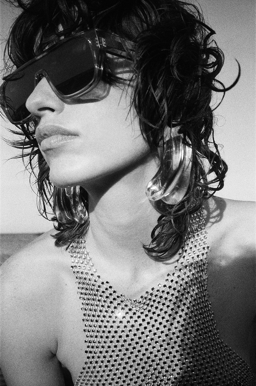 Short-haired woman in profile wearing a pair of sunglasses and a tank top