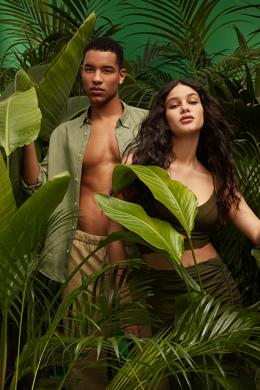 a couple of models with a background of plants simulating the Amazonian jungle on a green background