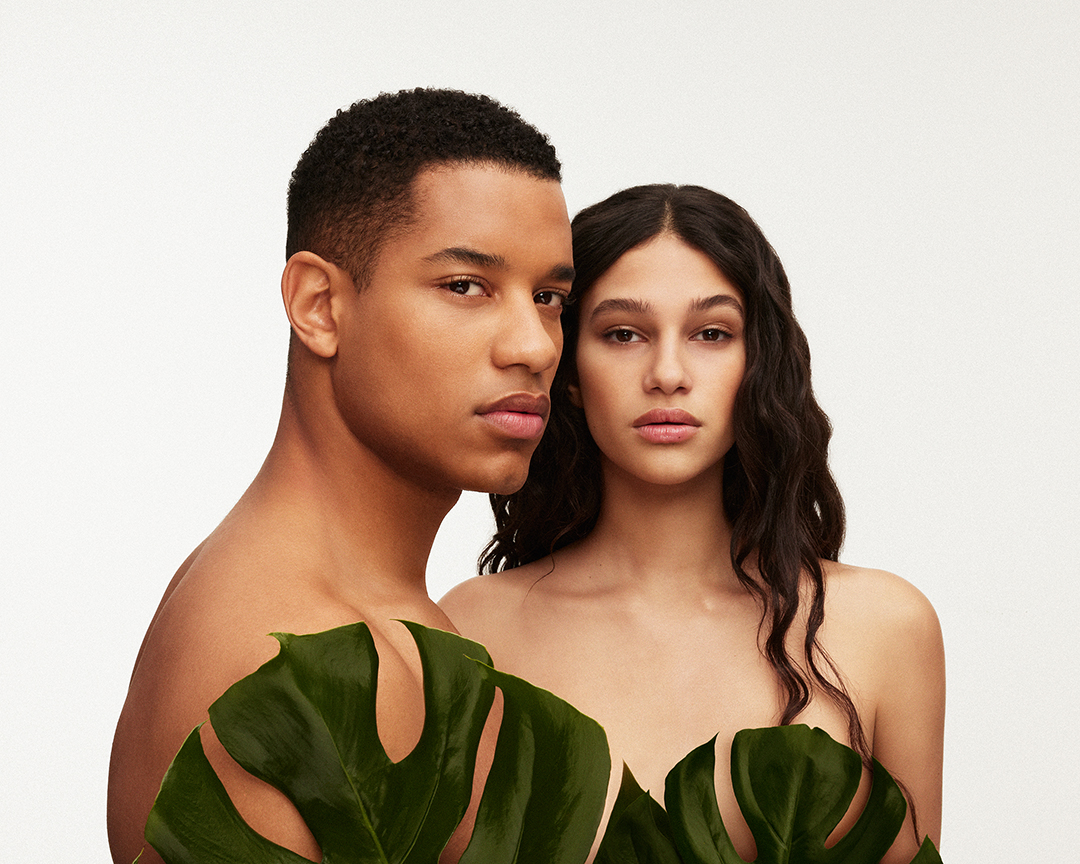 short shot of two models on a white background with plants covering the upper part of the body