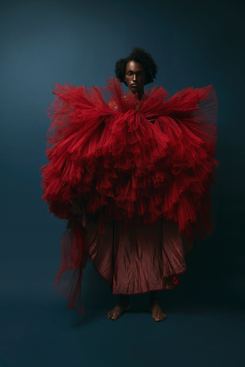 Full shot of a boy in a very extravagant red dress for Herdes magazine. 
