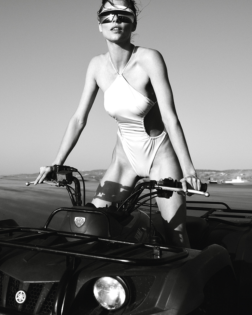 Black and white photo of the model driving a quat through the dry river mouth for Instyle's sports editorial.