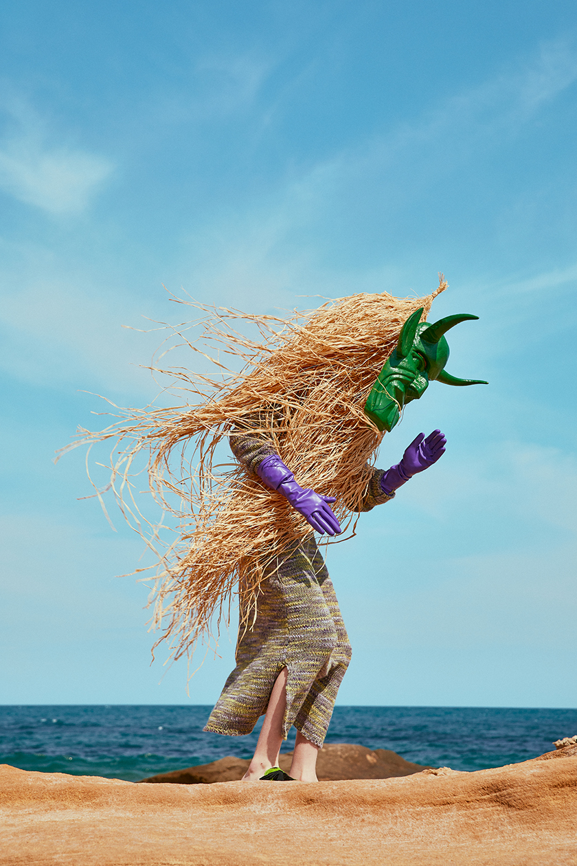 Person with a mask of a green monster looking at the sea. 