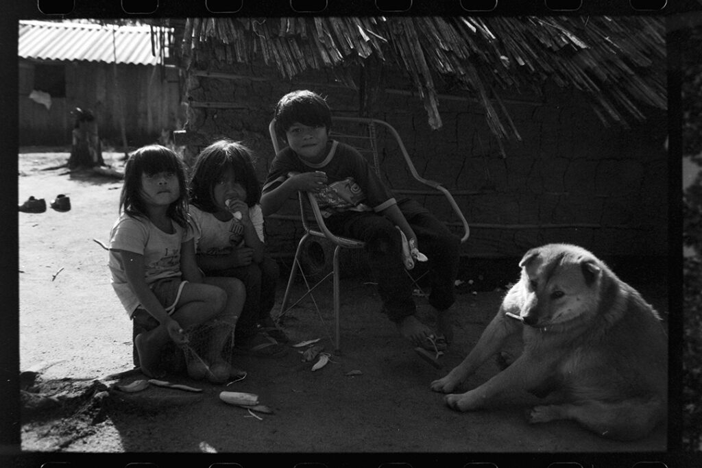 Black and white photo of 4 children sitting with a dog next to them in Brazil