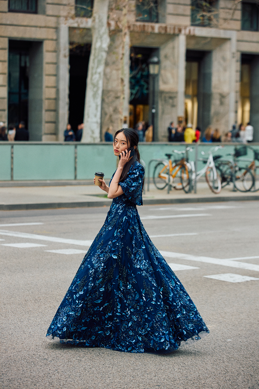 A woman walking down the street and talking on her mobile phone, wearing a Ze Garcia dress. 