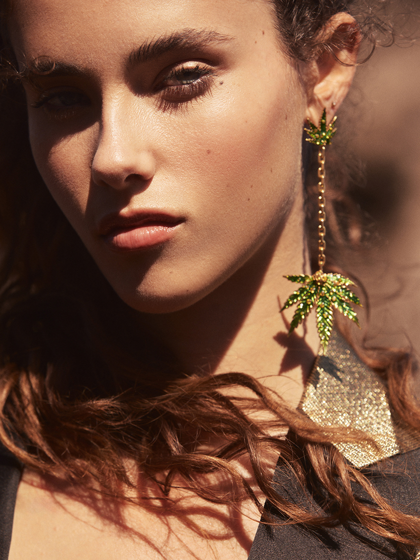 A girl looks at the camera, wearing green sparkling earrings, for the new issue of GQ Mexico.