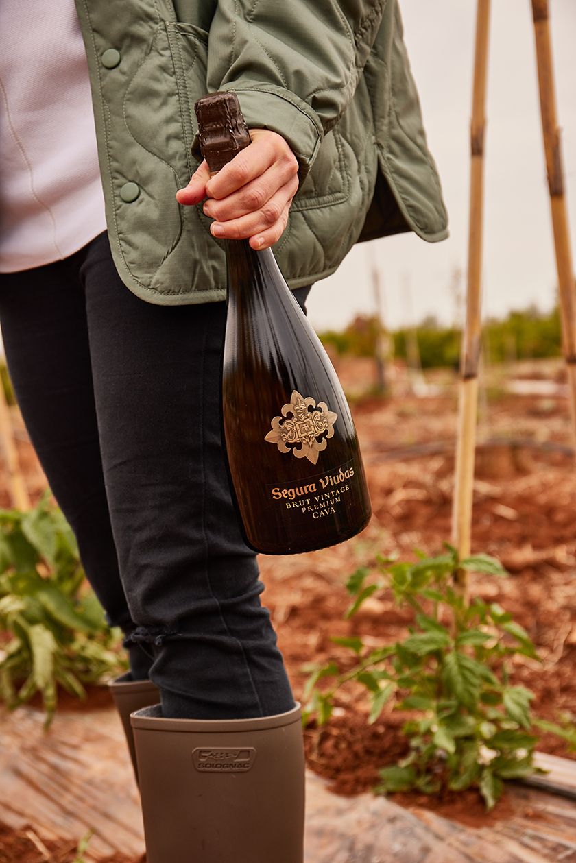 Vicky Sevilla strolling through her orchard with a bottle of Segura Viudas cava. 