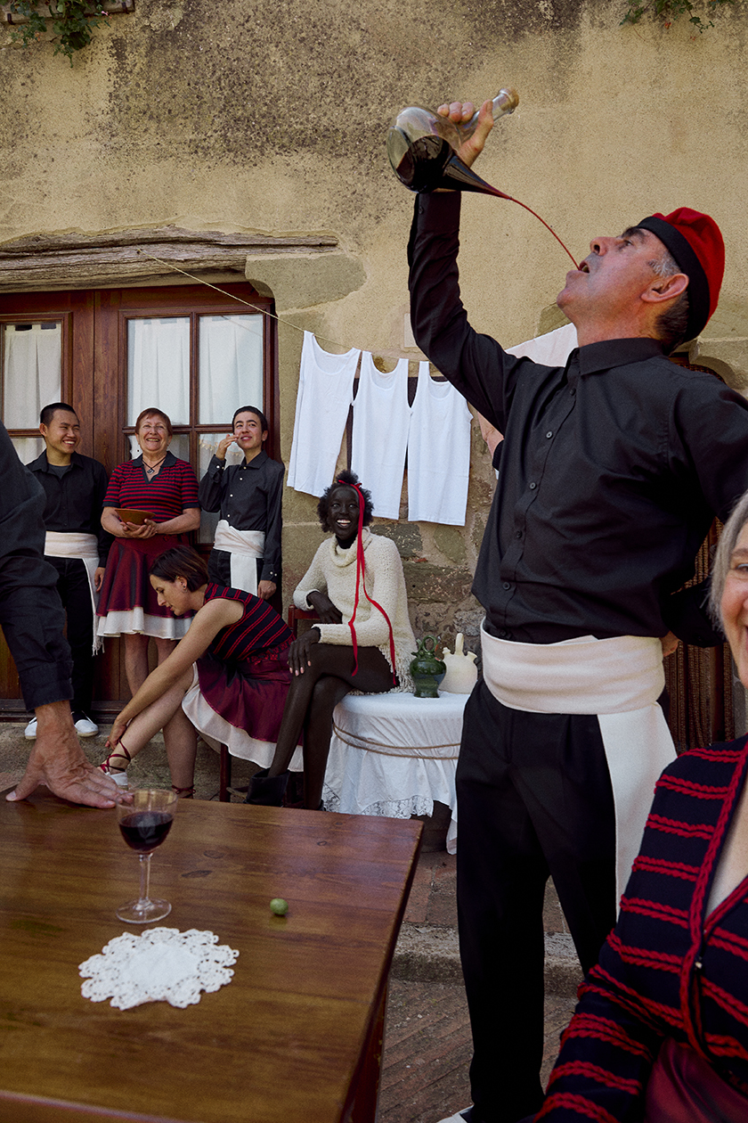 Model and group of typical catalan dancers drinking wine in the square of a catalan village for the magazine Numéro Netherlands. 