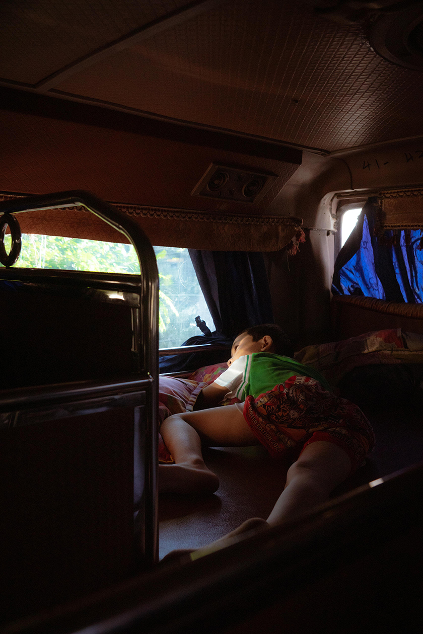 child stretched out in the bed of a moving train looking at the passageway.