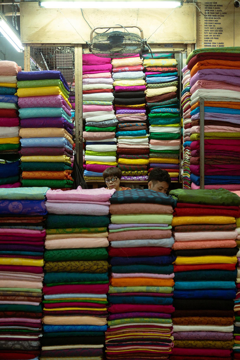 Women working in the textile industry with various coloured sarongs in front of them.