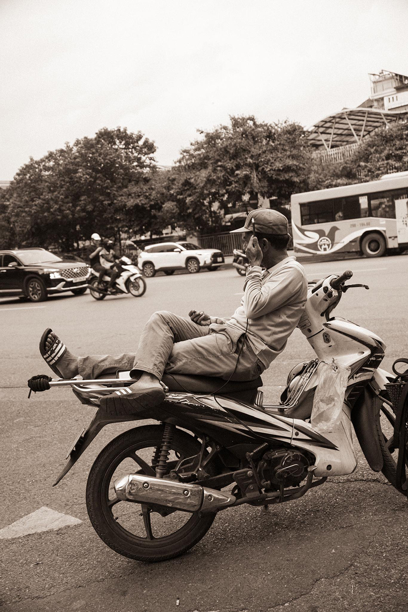 Man stretching out on a motorbike watching the traffic go by. 