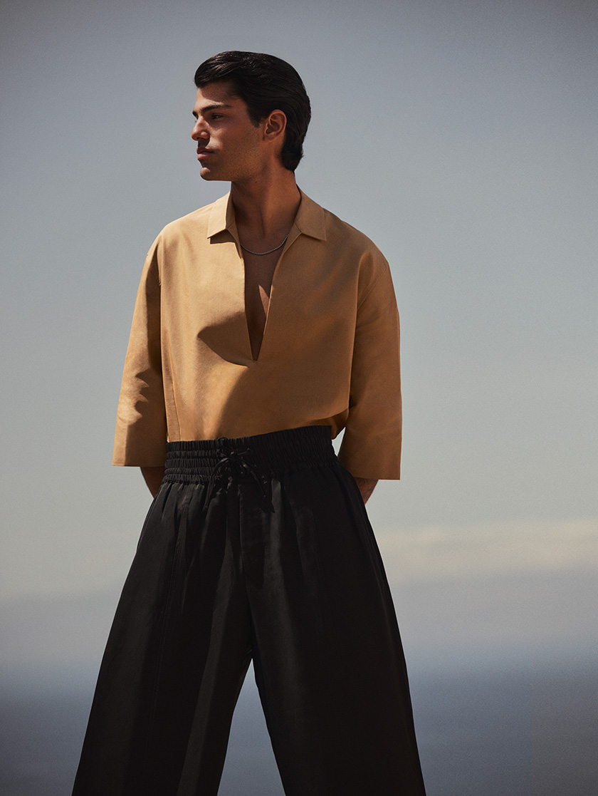 Model in profile with a suit in a sandy passage. 