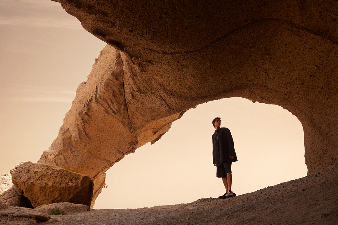 Model under a large stone deformed by the force of nature for the magazine Vogue Arabia.