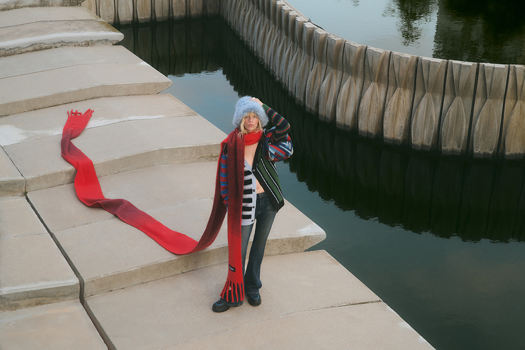 Image for Desigual's winter campaign with a model wearing a long red scarf that reaches down to the ground. 