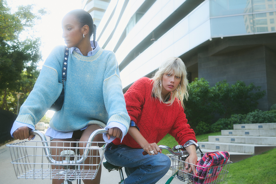 Image of the new winter collection with two models cycling through the streets of Barcelona.