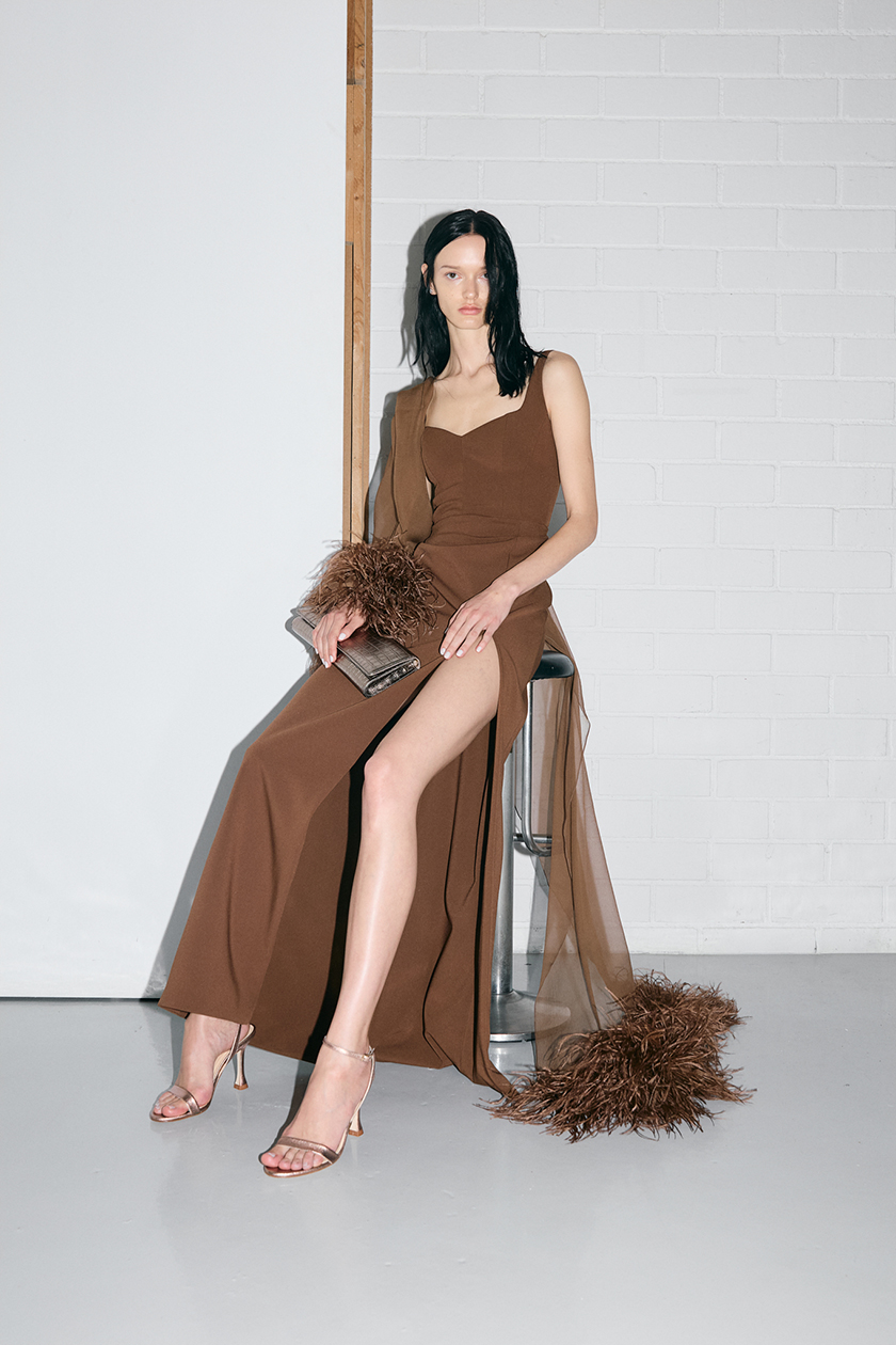 Model sitting on a stool wearing a long brown dress from the new Bambalina collection by Zegarcia.