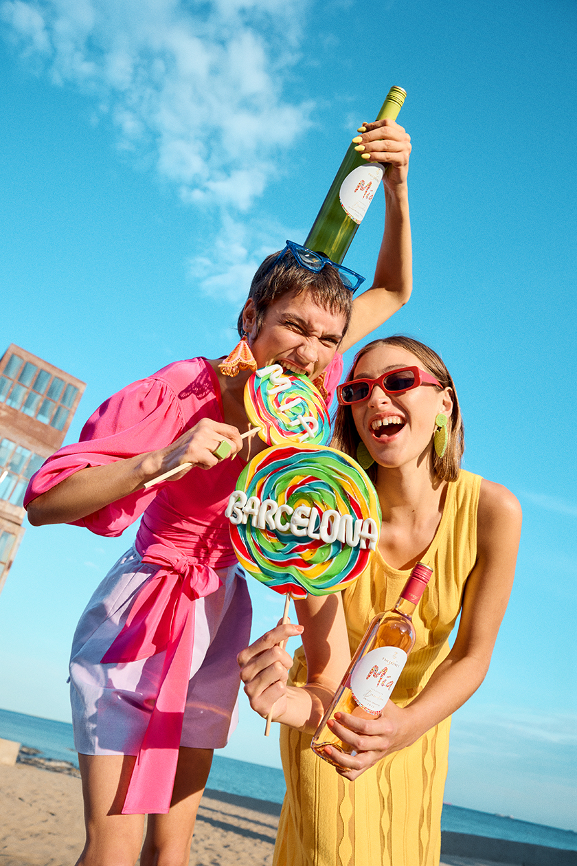Two models with lollipops on the beach in Barcelona holding one of the new bottles of Freixenet's Mía brand.